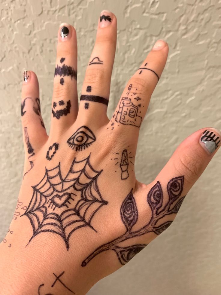 A hand with various doodles on it; including a heart-shaped spider web, a plant with eyes on the leaves, simple lava lamp and gun designs, and bands of different patterns on the fingers. Sharpie Hand Doodles, Simple Hand Tattoos, Pola Tato, Sharpie Doodles, Pretty Hand Tattoos, Finger Tattoo Designs, Pen Tattoo, Sharpie Tattoos, Hand Doodles