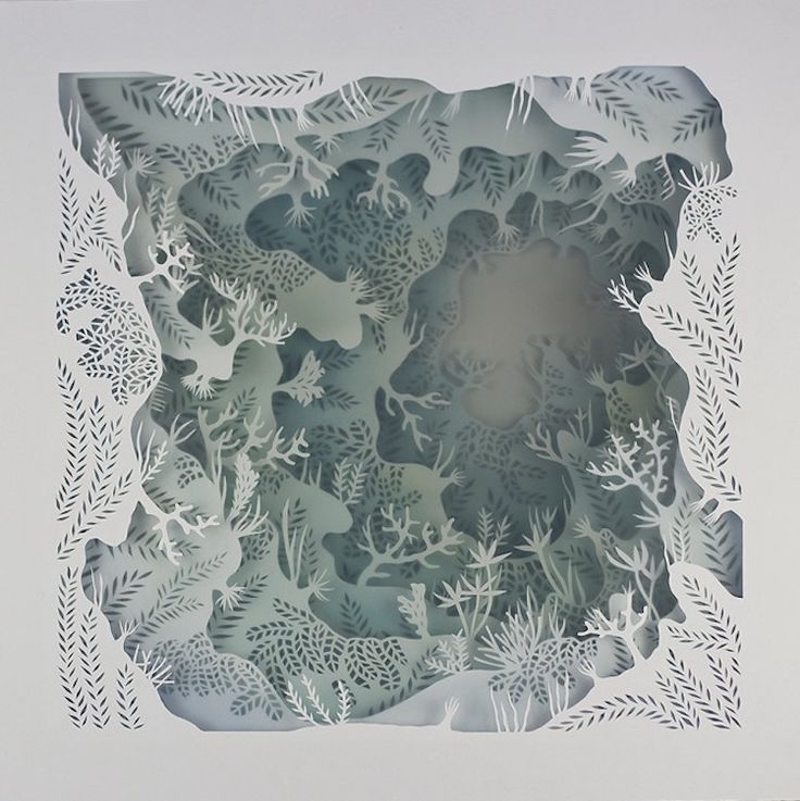 an intricate cut paper art piece with white flowers and leaves in the center on a gray background