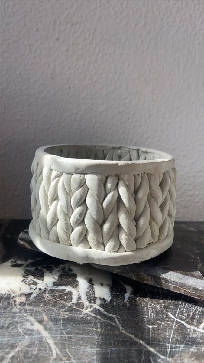 a white ceramic bowl sitting on top of a table next to a black and white wall