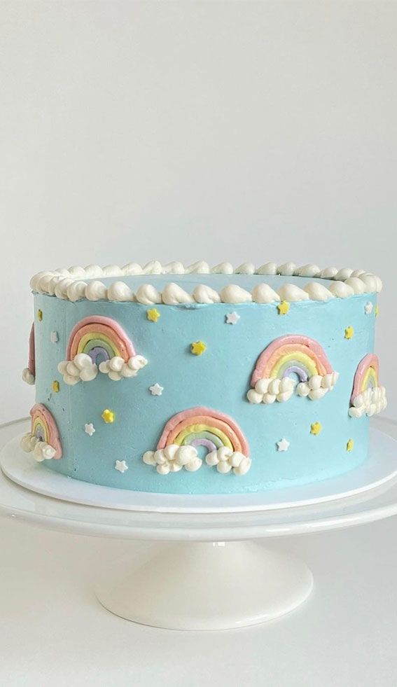 a blue cake decorated with rainbows and clouds