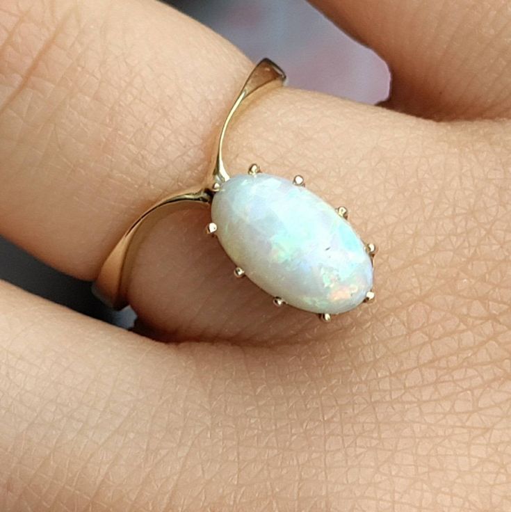 "This is one of those rings that would appear to be truly one of a kindI have seen so many opal rings, antique and modern, but I have never seen one with such an elegant and arresting structure. A flat pure yellow gold shank twists into a narrowing wishbone form, and the \"caged\" precious opal cabochon--in all likelihood an Australian opal--contained by narrow and somewhat long prongs, seems to ascend, glorious in its elevated North/South orientation. It is a tremendously elegant ring, one whic Timeless Oval Opal Ring As Gift, Timeless 14k Gold Opal Ring As Gift, Classic Formal Opal Rings, Classic Opal Rings With Birthstone, Minimalist Oval Opal Ring In 14k Gold, Minimalist 14k Gold Oval Opal Ring, Classic Opal Birthstone Ring, Minimalist Oval Opal Ring For Anniversary, Classic Opal Ring