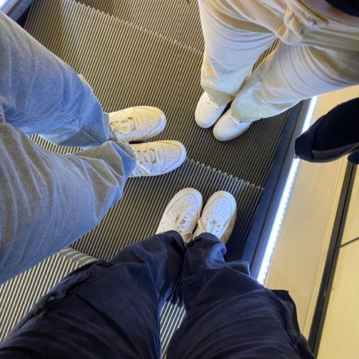 three people standing on an escalator with their feet up and one person wearing white shoes