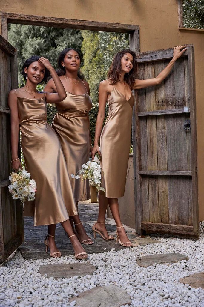 three bridesmaids in gold dresses posing for the camera