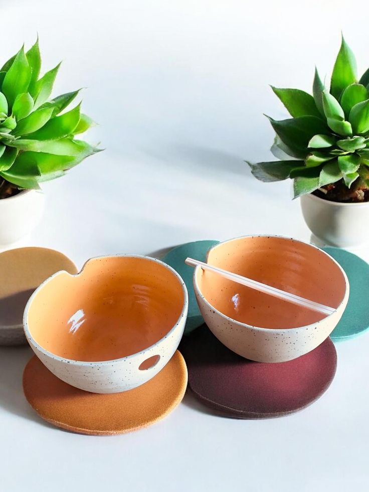 four bowls and two plates with plants in them on a white tableclothed surface