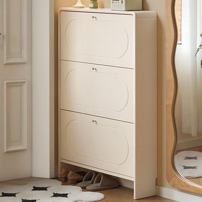 a white dresser sitting in front of a mirror next to a floor mat with shoes on it