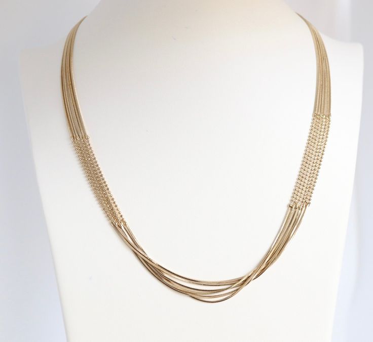 The elegant gold layered necklace boasts a sophisticated design with beaded sections on both sides, adding a touch of refinement and charm. Its multi-layered structure creates a statement piece that gracefully enhances any neckline, making it a versatile and eye-catching addition to your jewelry collection. Elegant Double Strand Metal Chain Necklace, Gold-tone Multi-strand Necklaces For Layering, Elegant Layered Chain Necklace For Formal Occasions, Elegant Gold-tone Chain Necklace For Layering, Formal Double Strand Metal Necklace, Chic Gold-tone Multi-strand Jewelry, Chic Multi-strand Gold-tone Jewelry, Elegant Double Strand Metal Layered Necklace, Multi-strand Beaded Chain Necklace