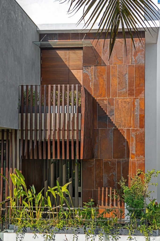 an apartment building that has a metal fence in front of it and lots of plants on the other side