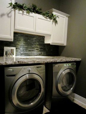 a washer and dryer in a small room with white cupboards on the wall