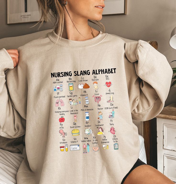 a woman is sitting on her bed wearing a sweatshirt with the words nursing sling alphabet printed on it