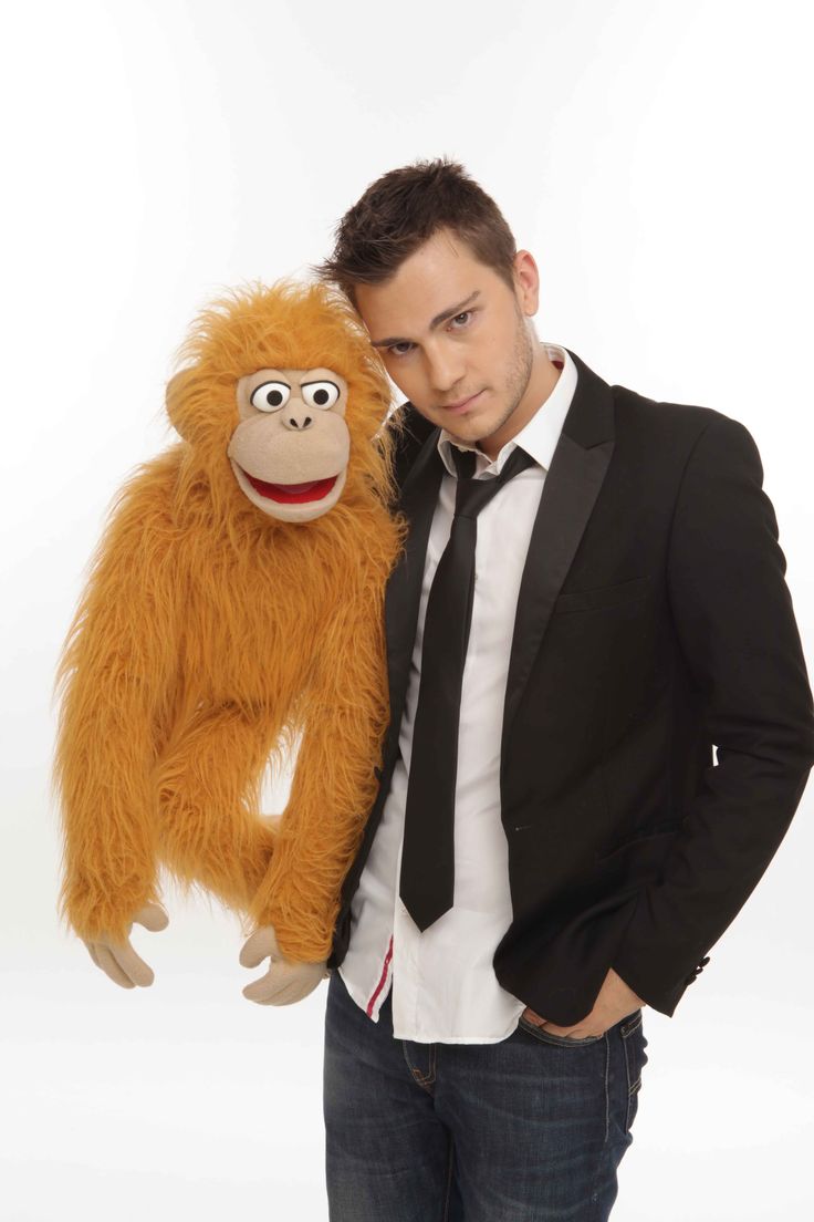 a man in a suit and tie standing next to a stuffed animal oranguel