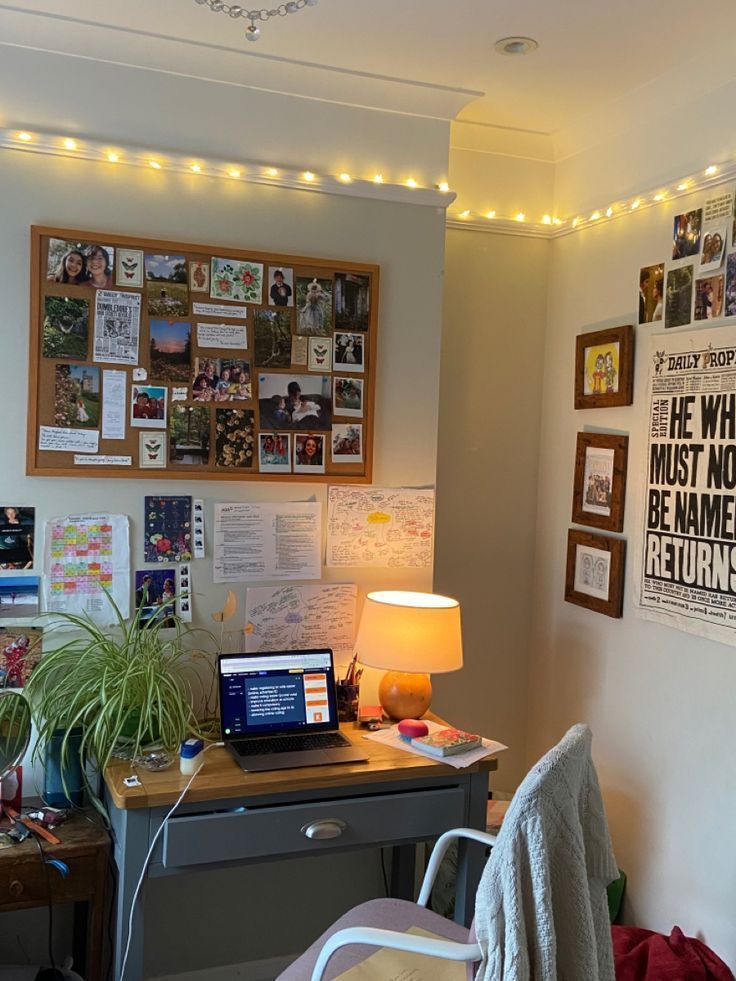 a desk with a laptop computer on top of it next to a wall covered in pictures