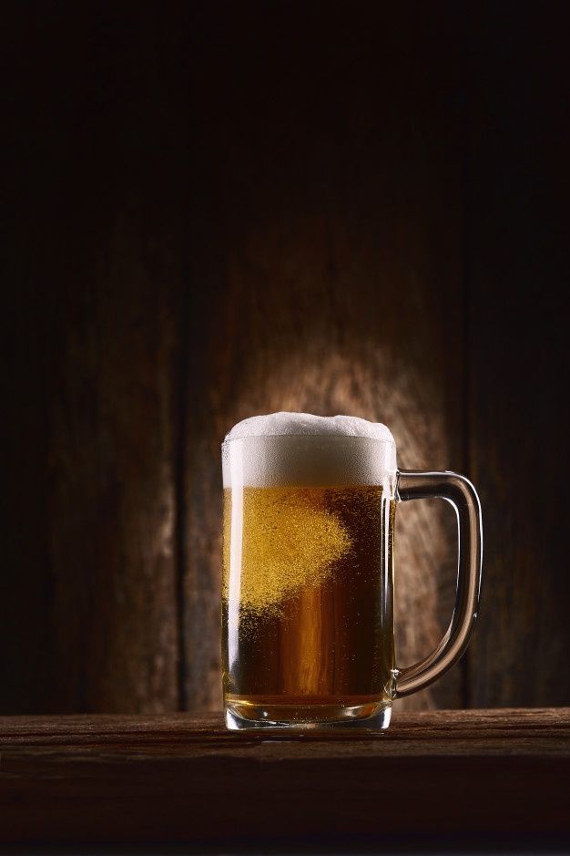 a mug of beer sitting on top of a wooden table