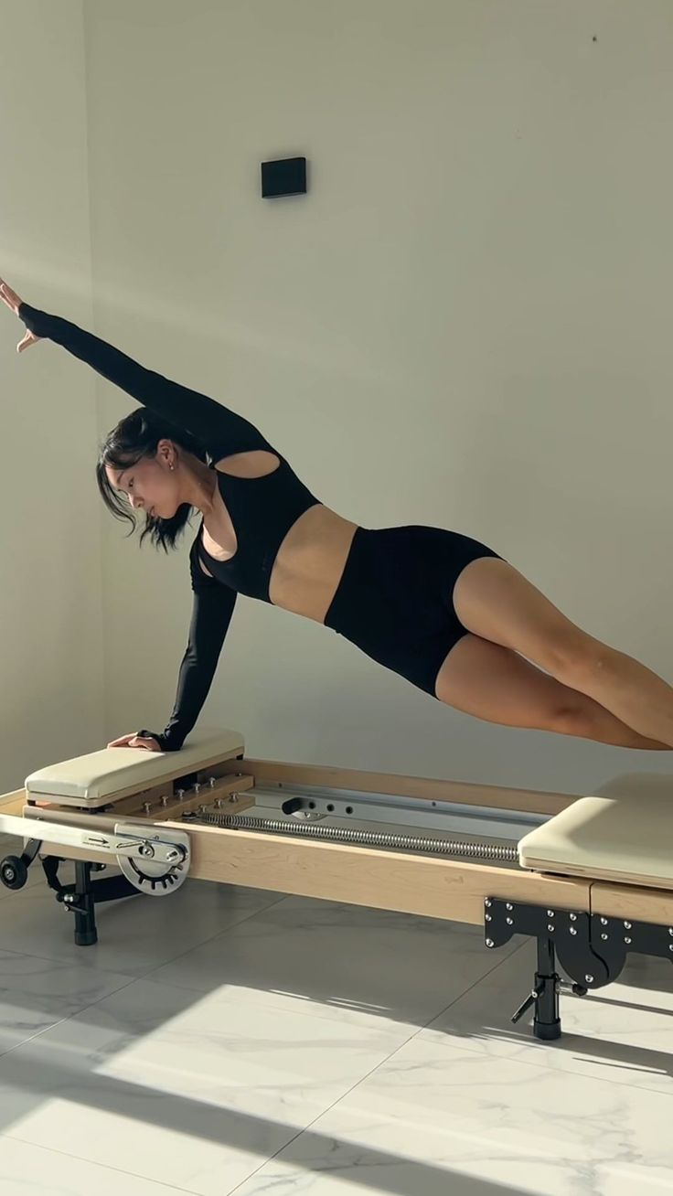 a woman in black shirt and shorts doing exercises on a piyom board with wheels