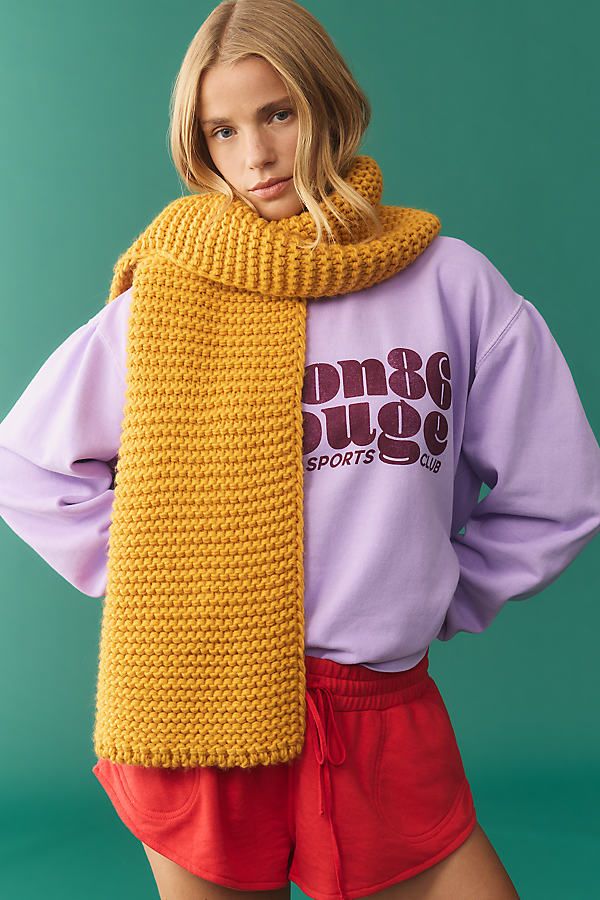 a woman wearing a yellow knitted scarf over her neck and sweater on top of her head