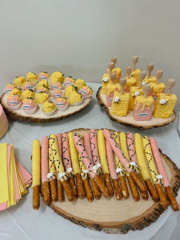 a table topped with cakes and desserts covered in yellow frosting on top of wooden slices