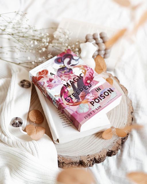 a book sitting on top of a tree stump next to flowers and beads in the background