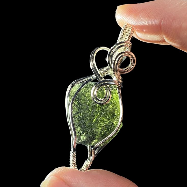 Moldavite from Chlum, South Bohemia, Czech Republic & sterling silver wire wrapped pendant. Please note that some photos have been backlit to show color and detail of the stone. All pendants come in a jewelry gift box with a small polishing cloth and black waxed cord included. Stone alone: 3.72 grams Completed pendant: 50 x 20 x 12 mm. 8 grams. Sterling Silver Jewelry With Natural Inclusions As Gift, Soldered Amber Jewelry Gift, Gift Amber Jewelry With Soldered Detail, Amber Soldered Jewelry Gift, Amber Soldered Jewelry For Gift, Collectible Silver Wire Wrapped Jewelry, Hand Wrapped Green Sterling Silver Jewelry, Mineral Jewelry, Tourmaline Jewelry