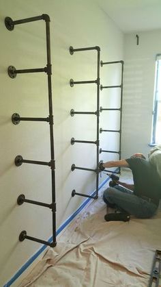 a man laying on the ground in front of a wall with pipes attached to it