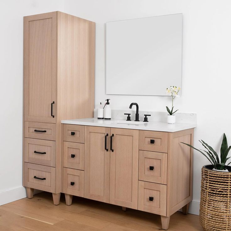 a bathroom vanity with two sinks and a mirror on the wall above it, next to a plant in a wicker basket