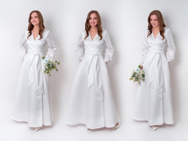 three women in long white dresses standing next to each other with flowers on their waist