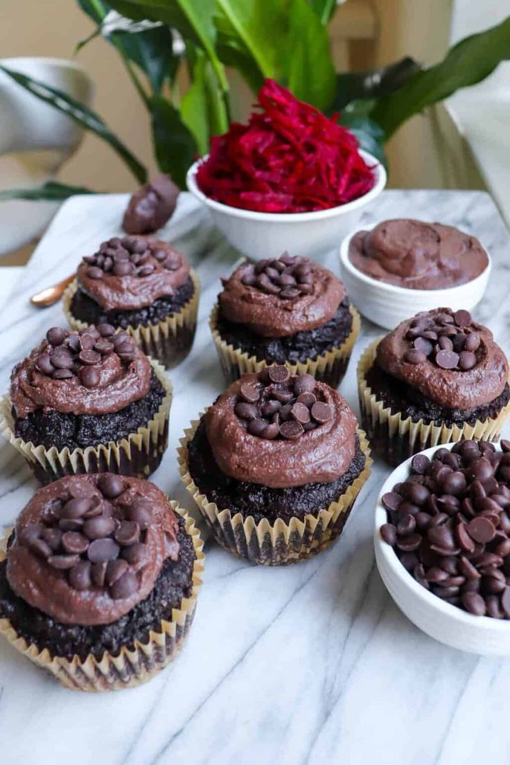 cupcakes with chocolate frosting on top and red flowers in the background text reads healthy chocolate beetroot muffins