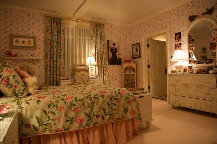 the bedroom is decorated in pink and green floral wallpaper, along with an antique dresser