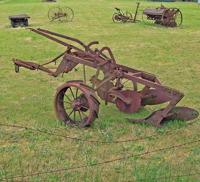 an old rusted out tractor sitting in the grass