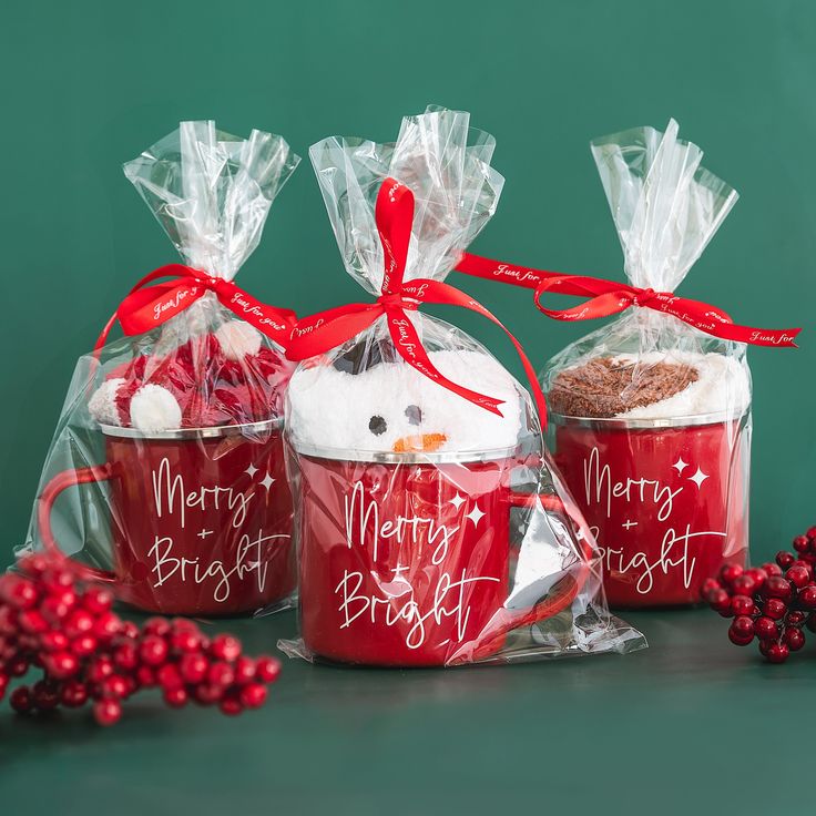 three red mugs with white frosting and christmas decorations