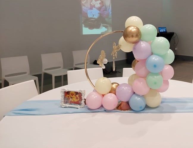 a table with balloons on it in front of a projector screen