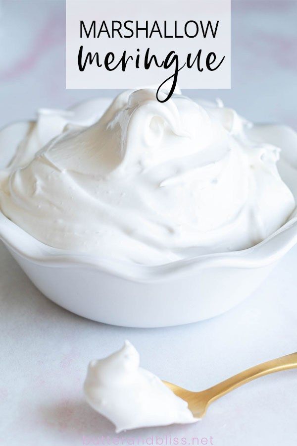 a white bowl filled with whipped cream on top of a table next to a spoon