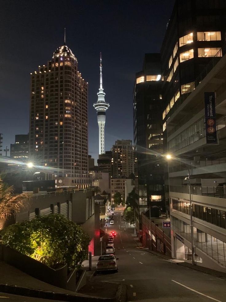 a city street at night with tall buildings in the background