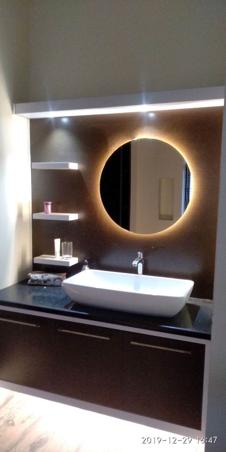 a bathroom with a sink, mirror and shelving unit on the wall above it