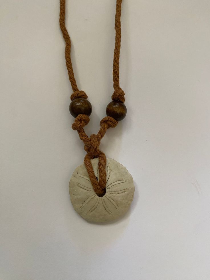 Handmade sand dollar necklace crafted with brown hemp cord and gemstone beads. Handmade Brown Necklace For Vacation, Casual Adjustable Jewelry With Round Pendant, Natural Casual Jewelry For Vacation, Casual Natural Jewelry For Beach, Casual Natural Jewelry For The Beach, Casual Natural Jewelry For Vacation, Adjustable Brown Beaded Necklace For Beach, Casual Brown Beaded Necklace For The Beach, Casual Brown Beaded Necklace For Beach