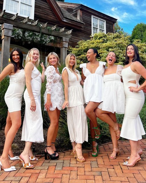 a group of women standing next to each other in front of a brick walkway and house