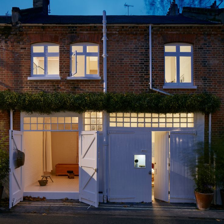 an open garage door in front of a brick building at night with the lights on