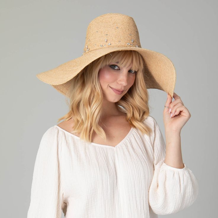 Our Glitz Wide Brim Fedora Sun Hat is a luxurious accessory for your summertime wardrobe. The delicate braid raffia is carefully crafted with attention to detail, and embedded with rhinestones to add a touch of sparkle. The 6" brim offers UPF 50+ sun protection and is adjustable for a perfect fit. Boasting a classic natural color and crafted from 100% premium raffia, this floppy fedora is a must-have for any fashionable collection. Features: Color: NaturalMaterials: 100% RaffiaBrim Size: 6" Brim Wide Brim Hat Summer, Sand Collection, Womens Fedora, Outdoor Cap, Wide Brim Fedora, Hat Clips, Summer Favorites, Scarf Poncho, Dress Hats