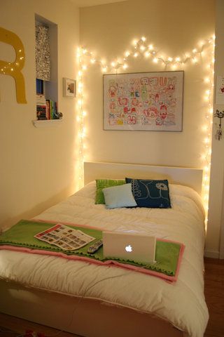 a bed with lights on the headboard and laptop computer sitting on top of it