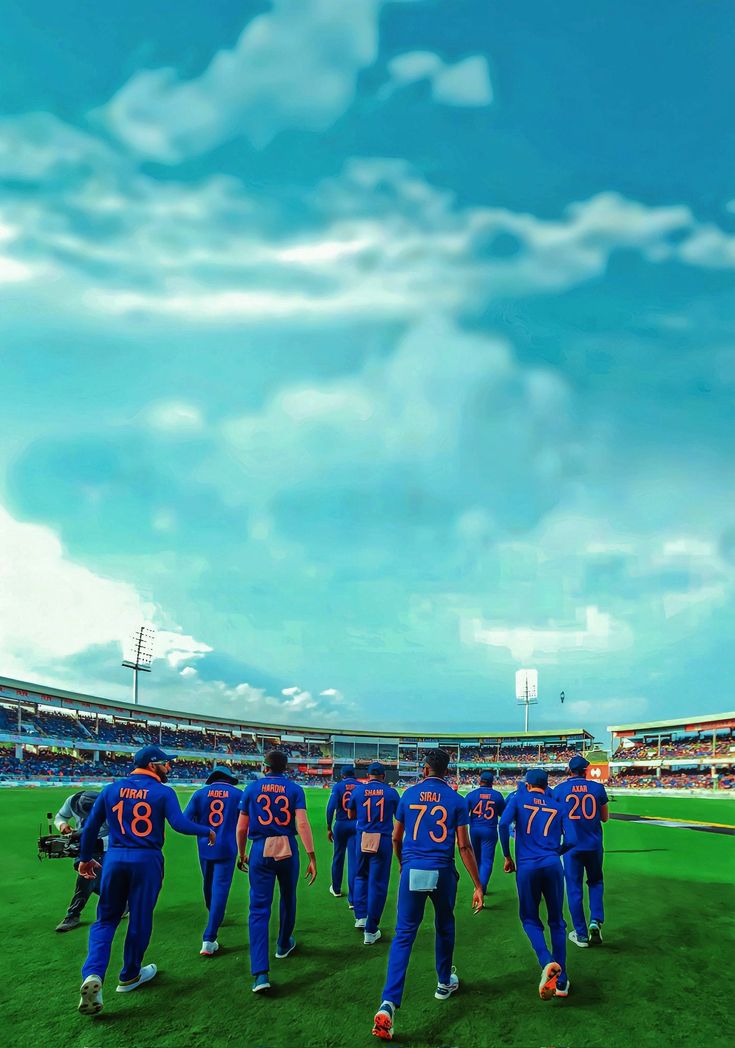 a group of men in blue uniforms walking across a field at a baseball game with the sky and clouds behind them