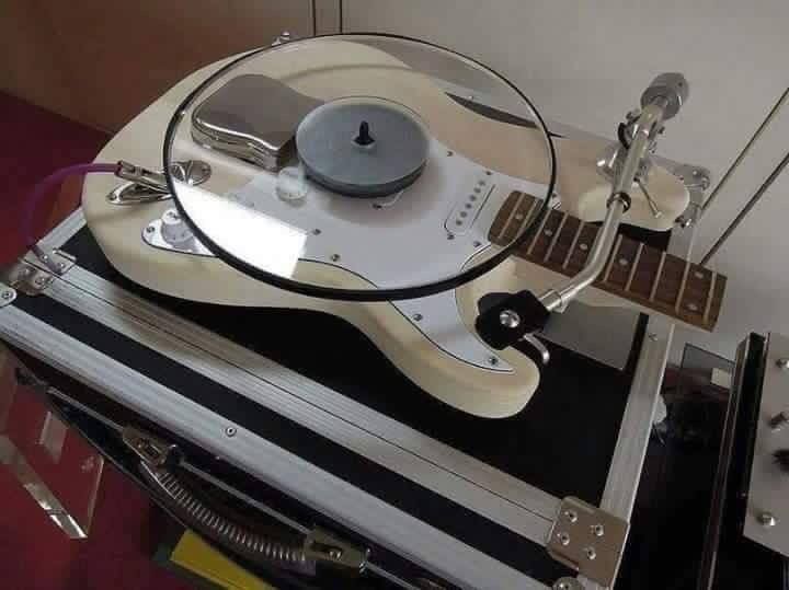 a record player sitting on top of a turntable with an electric guitar attached to it