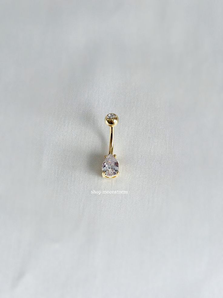 a single gold nose piercing with a clear stone in the center on a white background