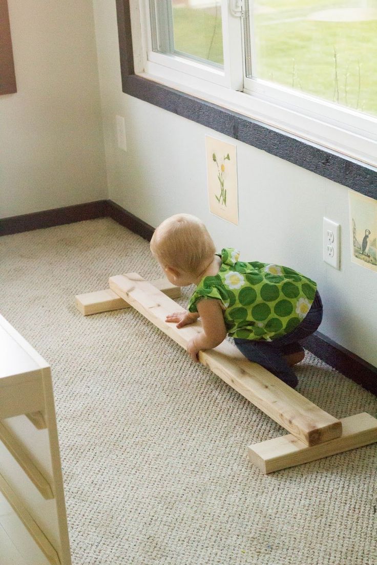 a little boy sitting on top of a wooden bench in front of a large window