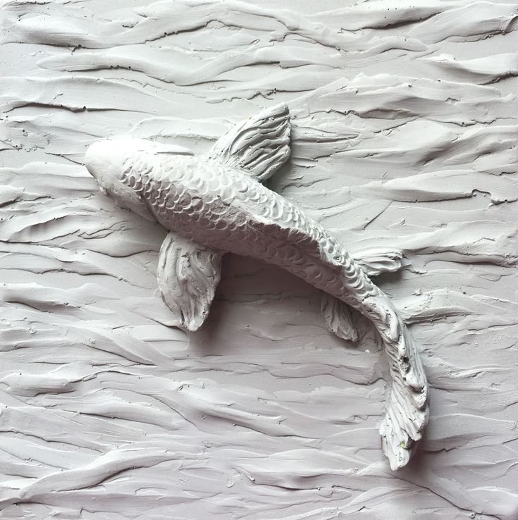 a white sculpture of a fish in the middle of some paint chippings on a wall