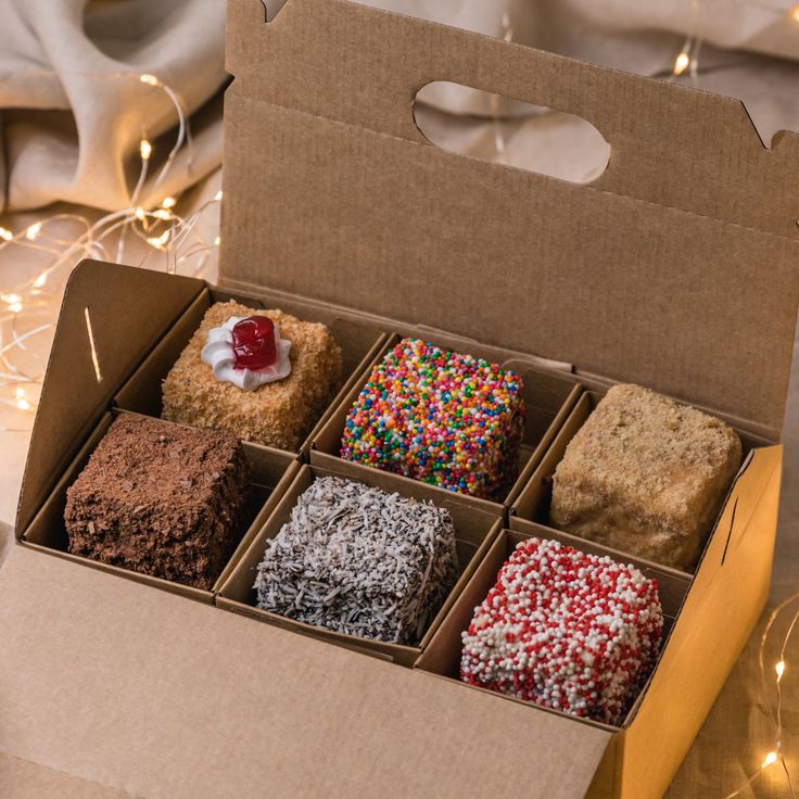 an open box filled with different types of donuts and sprinkles on top of a table