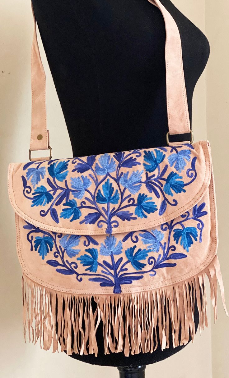 Kashmiri chain stitch floral embroidery on the front, The bag comes with a main compartment, a small zipper coin pocket inside and a zipper pocket when the embroidered flap is lifted, the flap also has a metal stud to keep it close.  The top of the bag has a wide, adjustable shoulder strap to convert from a cross body to hand bag.  The suede bag is lined and lightly padded. Each bag has unique beautiful floral embroidery on the front in vibrant colors, designed by artisans from Kashmiri, India. This bag is perfect as a crossbody or shoulder bag the options are endless. A bag to keep travel  Essential while traveling.  A gift for anyone that loves unique handmade keepsakes. Please select gifting options. Features: * Flap Cover * small zippered pocket under the flap * Inner zipper pocket * A Bohemian Crossbody Bag With Floral Embroidery, Embroidered Crossbody Shoulder Bag For Travel, Bohemian Multicolor Embroidery Bags As Gifts, Traditional Bags With Floral Embroidery, Bohemian Embroidered Bag For Everyday Use, Hand-stitched Travel Bags, Bohemian Embroidered Pouch Shoulder Bag, Bohemian Embroidered Crossbody Shoulder Bag, Travel Shoulder Bag With Floral Embroidery