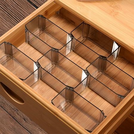 a wooden drawer with six clear glass containers in it on top of a wood table