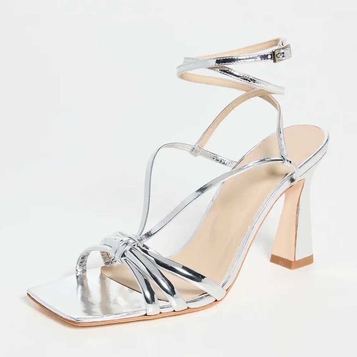 Elegant silver metallic heeled sandals with a square toe feature a wrap-around ankle Strap, combining modern flair and timeless sophistication for a striking ensemble. Color: Silver Heel Type: Flared heel Heel height: 3.5" / 90 mm approx Product measurements were taken using size 8. Please note that measurements may vary by size. Toe: Open square toe Wrap-around ankle strap design Handcrafted US sizing. Fits true to size. Spring Metallic Sandals With Wrapped Heel, Modern Silver Sandals With Ankle Strap, Spring Silver Sandals With Wrapped Heel, Chic Silver Heels With Single Toe Strap, Sleek Silver Heels With Wrapped Heel, Modern Silver Sandals With Pointed Toe, Modern Silver Heels With Padded Heel, Silver Sandals With Heel Loop And Pointed Toe, Sleek Silver Sandals For Summer