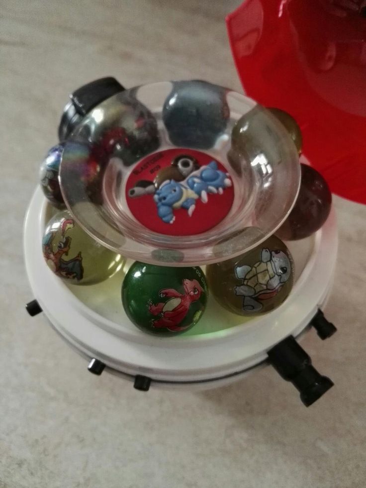 an assortment of glass balls in a bowl on top of a stand with magnets