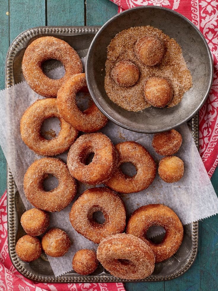 doughnuts are sitting on a tray next to a bowl of sugared donuts