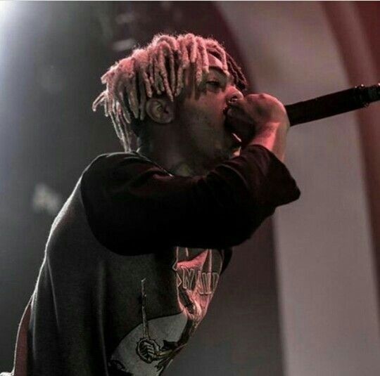 a man with dreadlocks holding a microphone up to his mouth while standing on stage