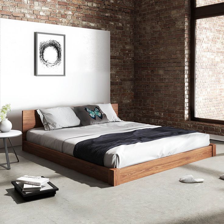 a bed sitting next to a window in a room with brick walls and flooring